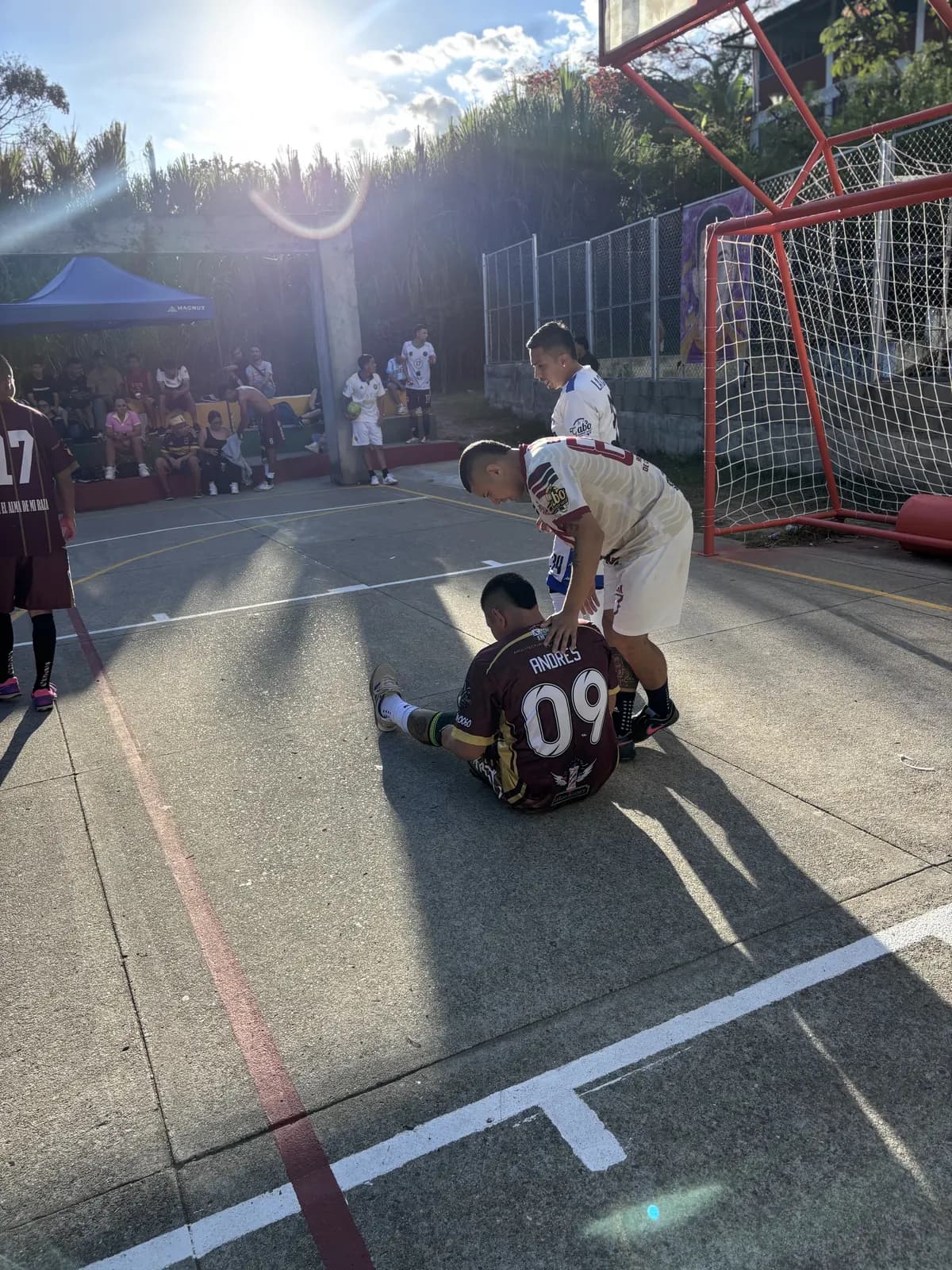 Un jugador ayuda a otro que está en el piso durante el partido